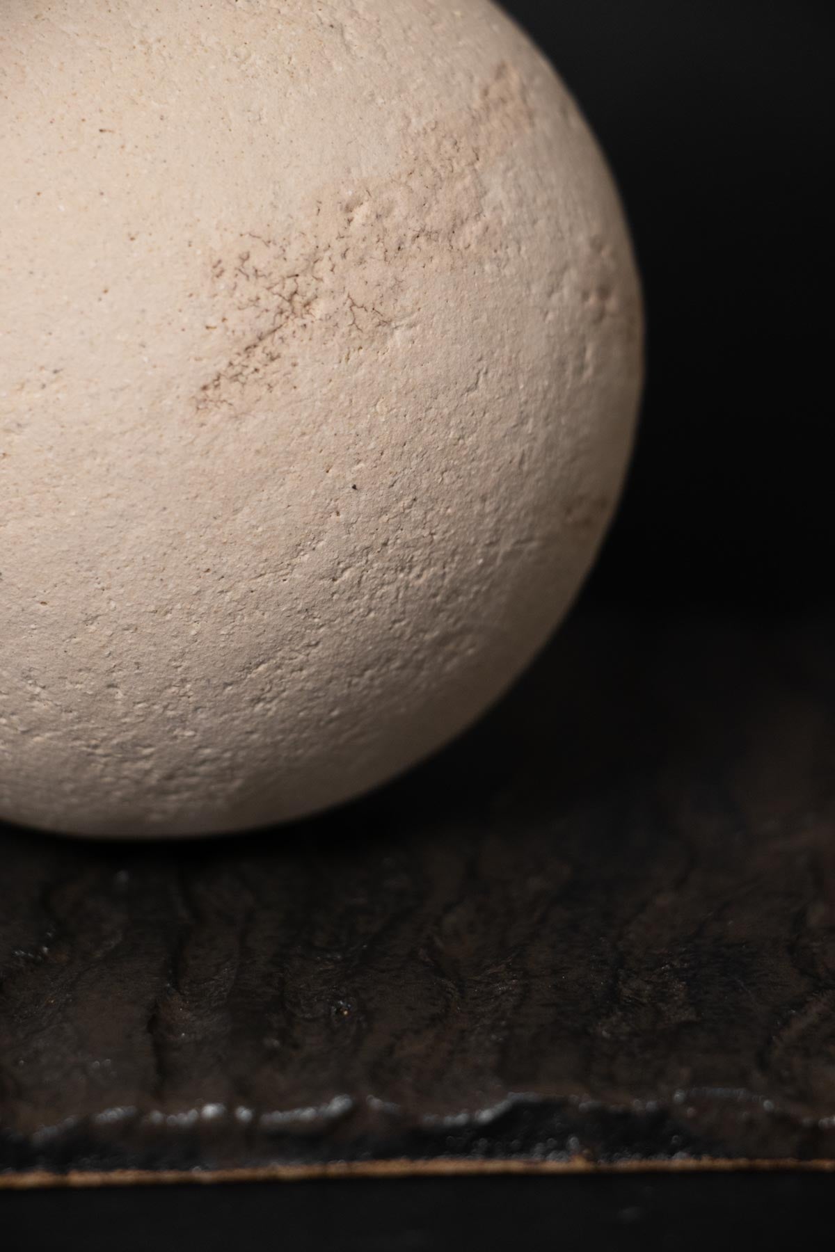 Close-up of a textured white sphere on a dark surface