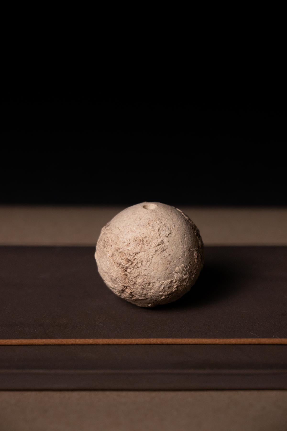 Textured sphere on a dark surface. Organic ceramic sphere. Incense holder. Design incense burner.
