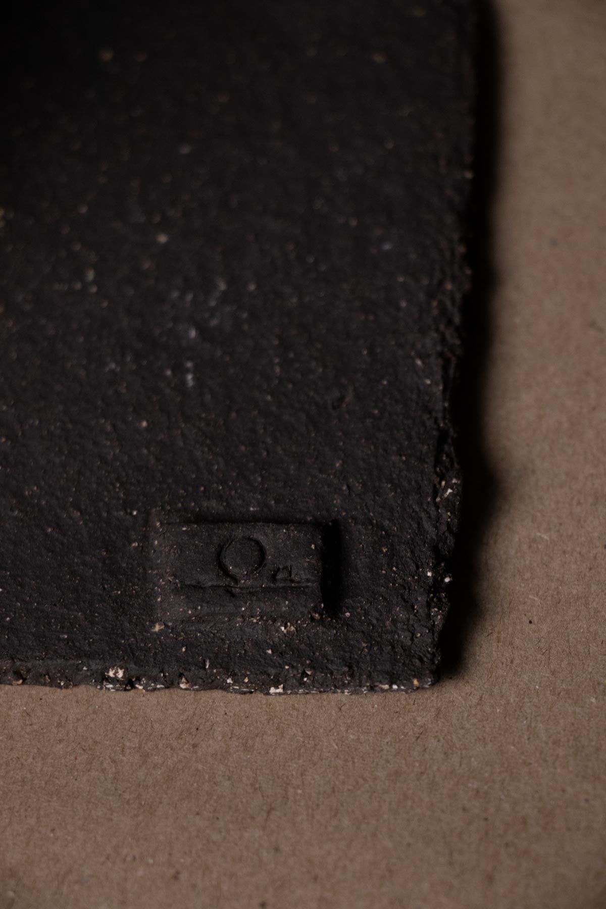 Close-up of Claire Lune logo on black clay.