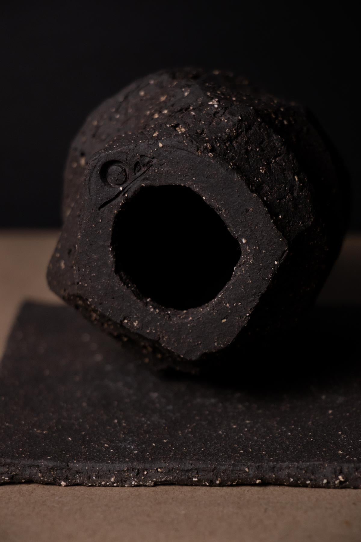 Close-up of hollow block of kurinuki incense burner. Claire Lune logo. Gritty stoneware. Ceramic incense burner. Black stoneware ceramics.