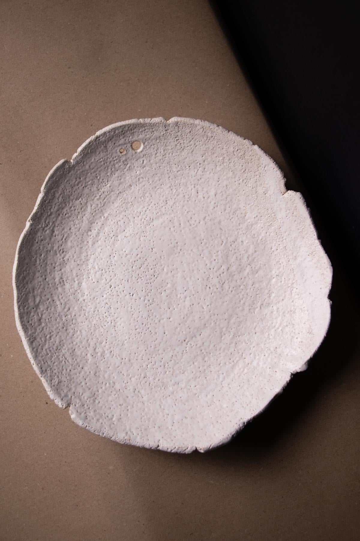 Round ceramic plate with textured surface on a brown background