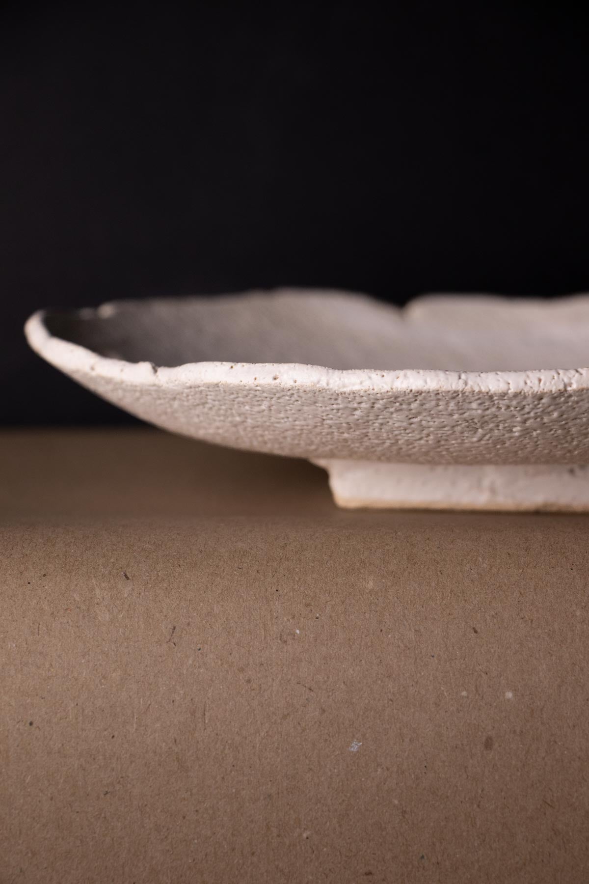 Close-up of a textured white ceramic plate with foot.