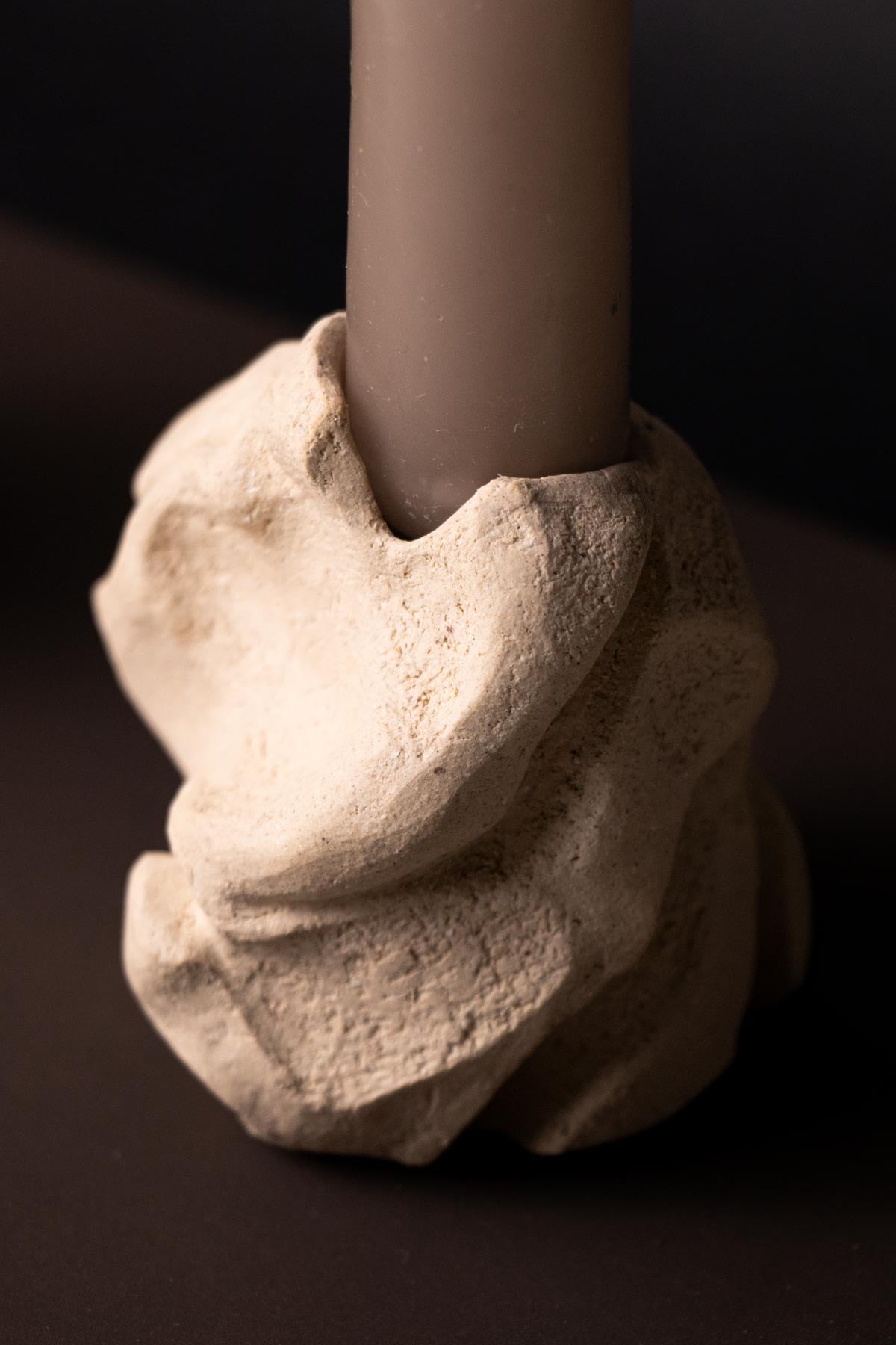 Decorative candle holder with a textured base on a dark background