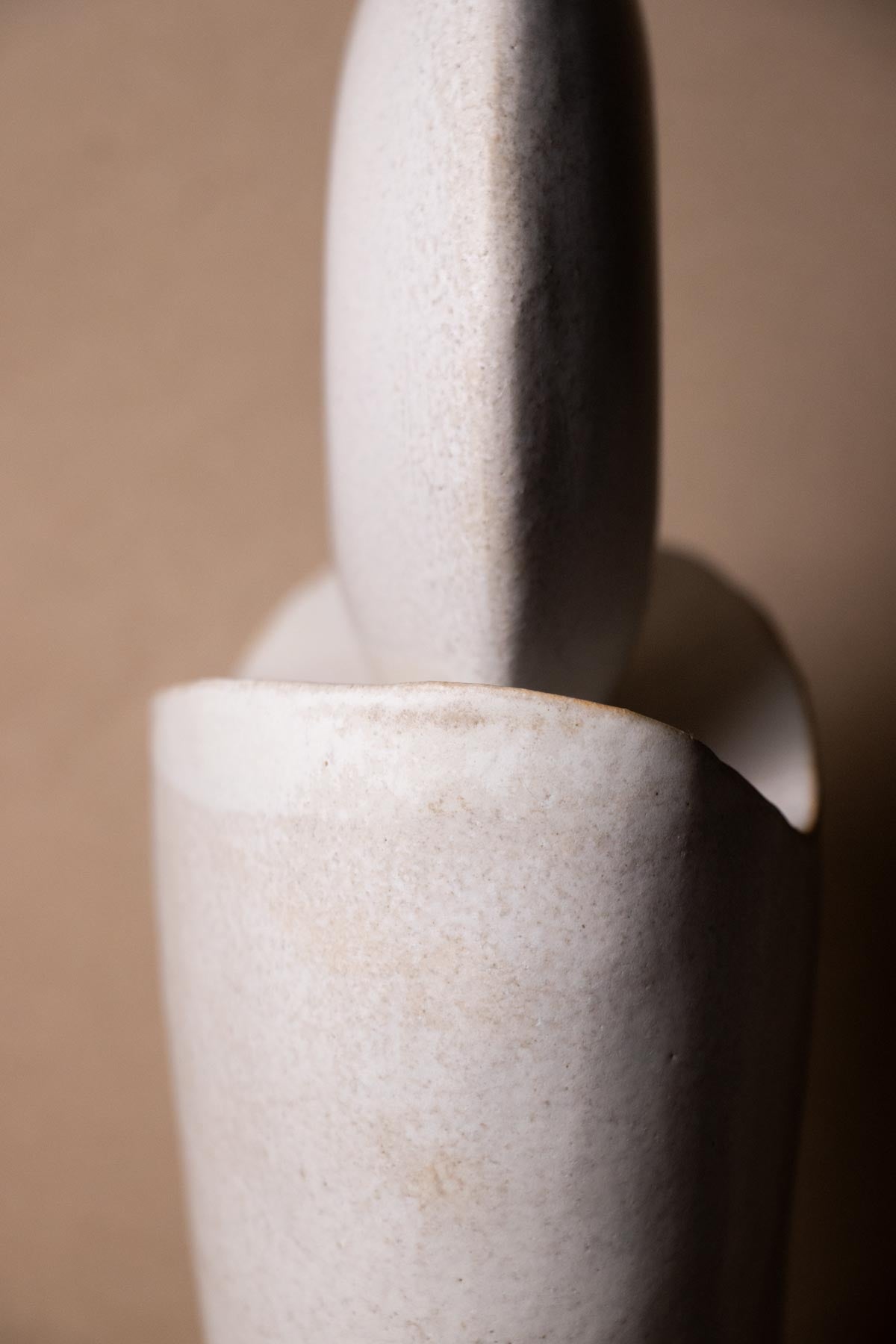 Close-up of a textured white ceramic sculpture against a beige background