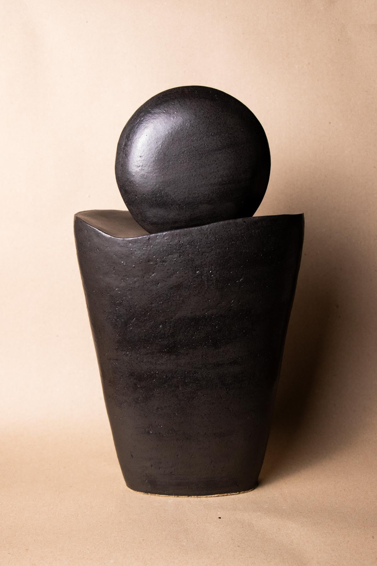 Black ceramic sculpture inspired by the moon. Minimalist stoneware sculpture. Minimalist decor. Decorative ceramics. In front of a plain white background. New moon sculpture. Italian ceramics.