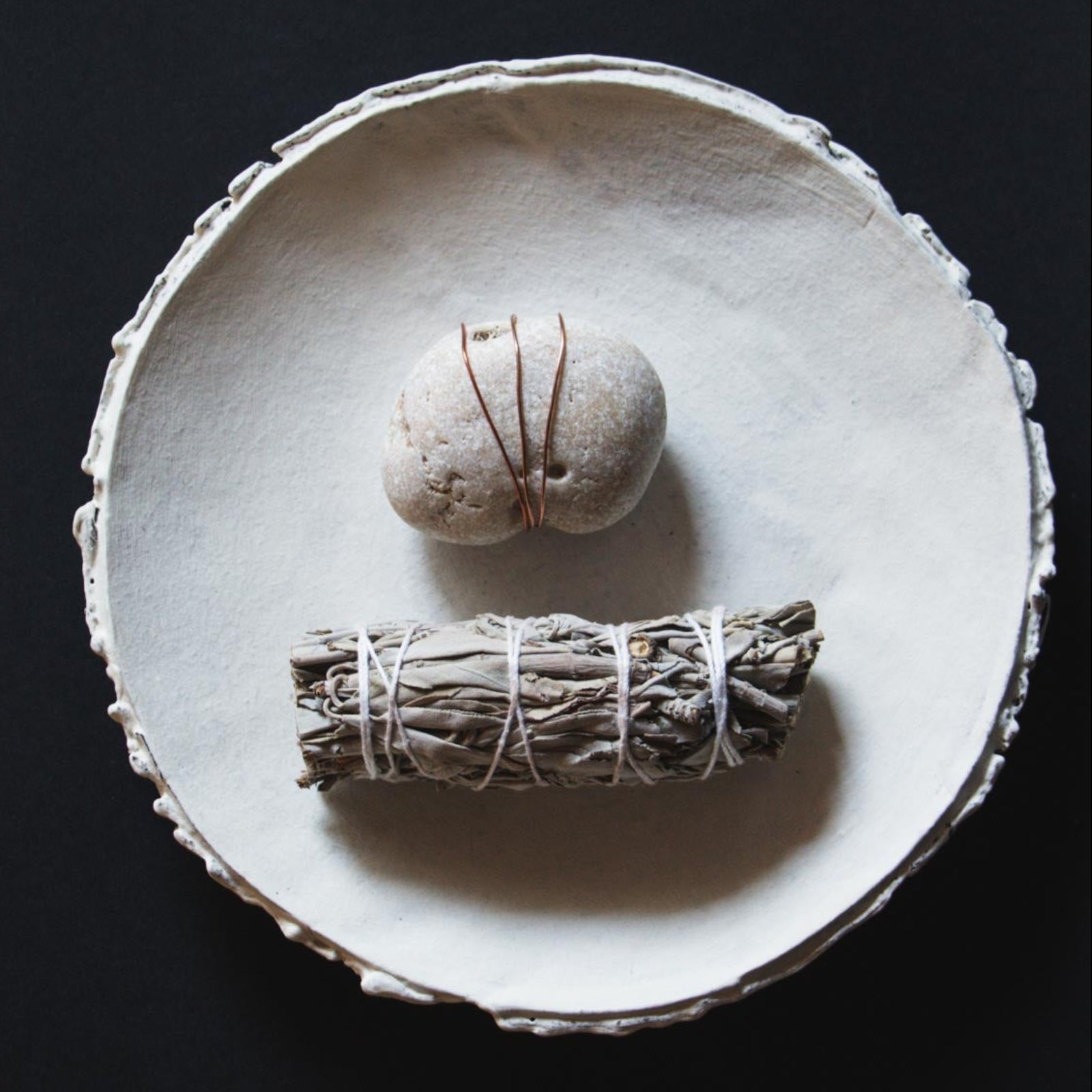 Ceramic plate with a bundle of sage on a dark background