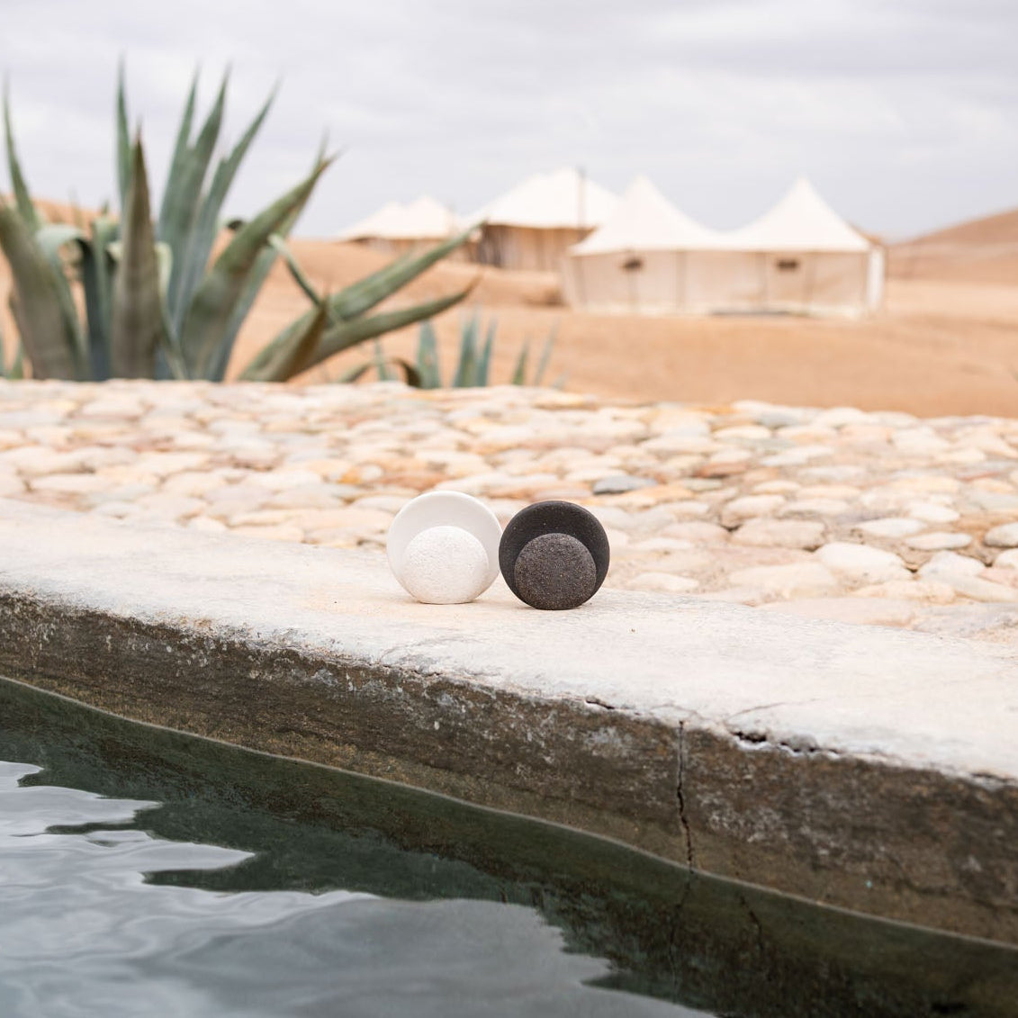 Nomad Luna incense burners styled in pool area with a stone deck and desert landscape in the background - Marrakesh