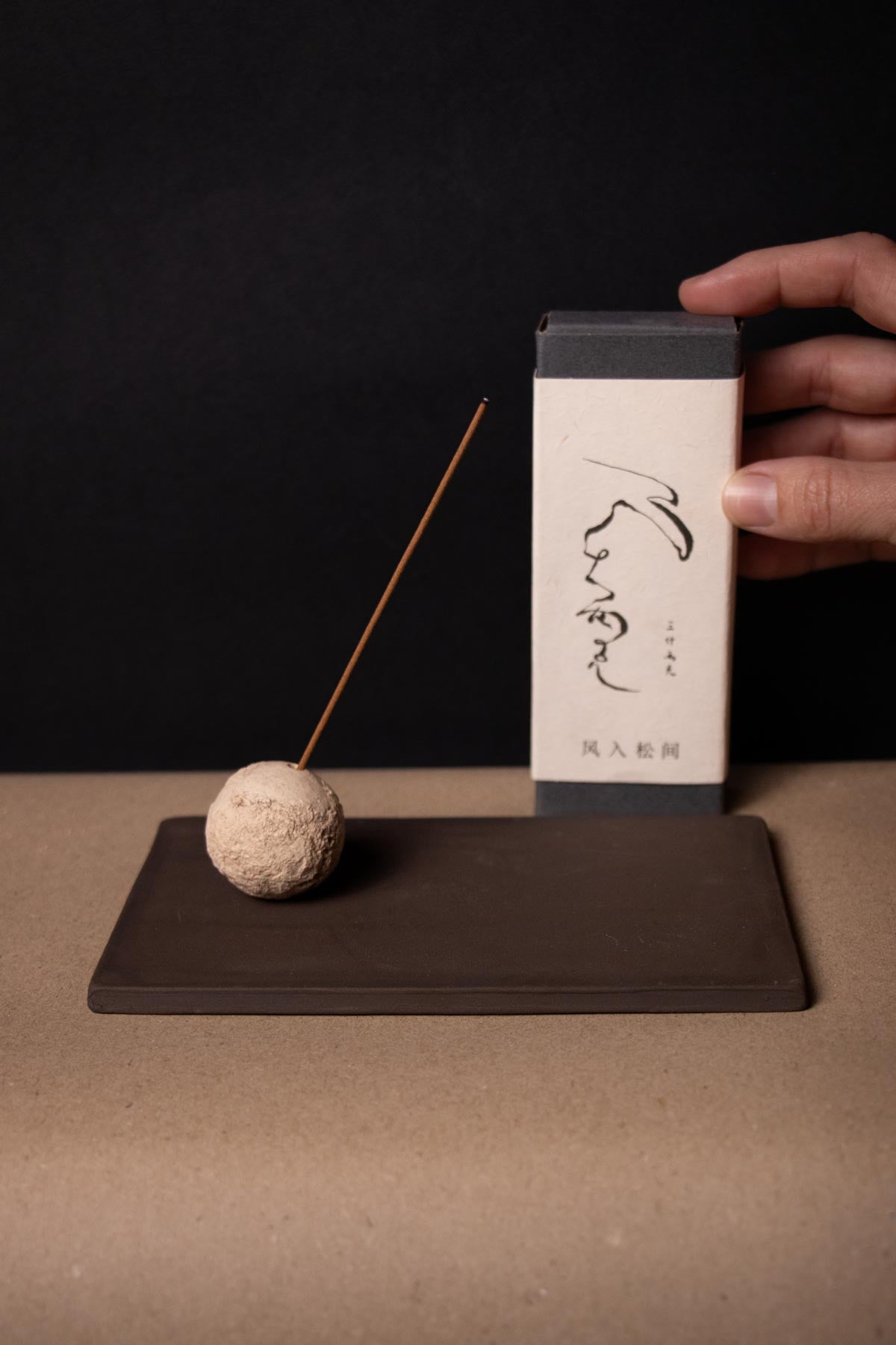 artistic incense burner. Ritual kit. ceramic incense stick holder. organic texture. Sphere holding incense stick on a brown tray. Incense stick box in the back ground. Chinese traditional incense.