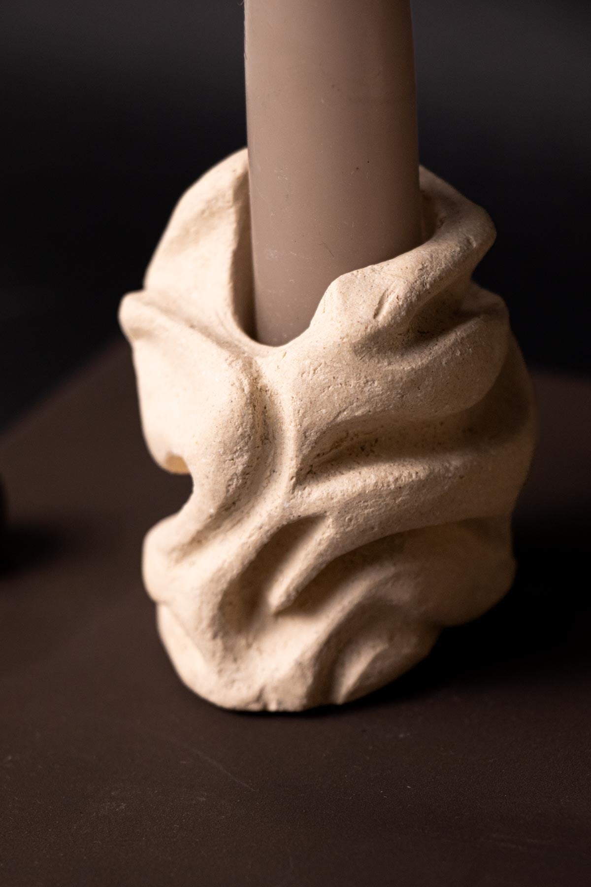 Decorative candle holder with a textured base on a dark background