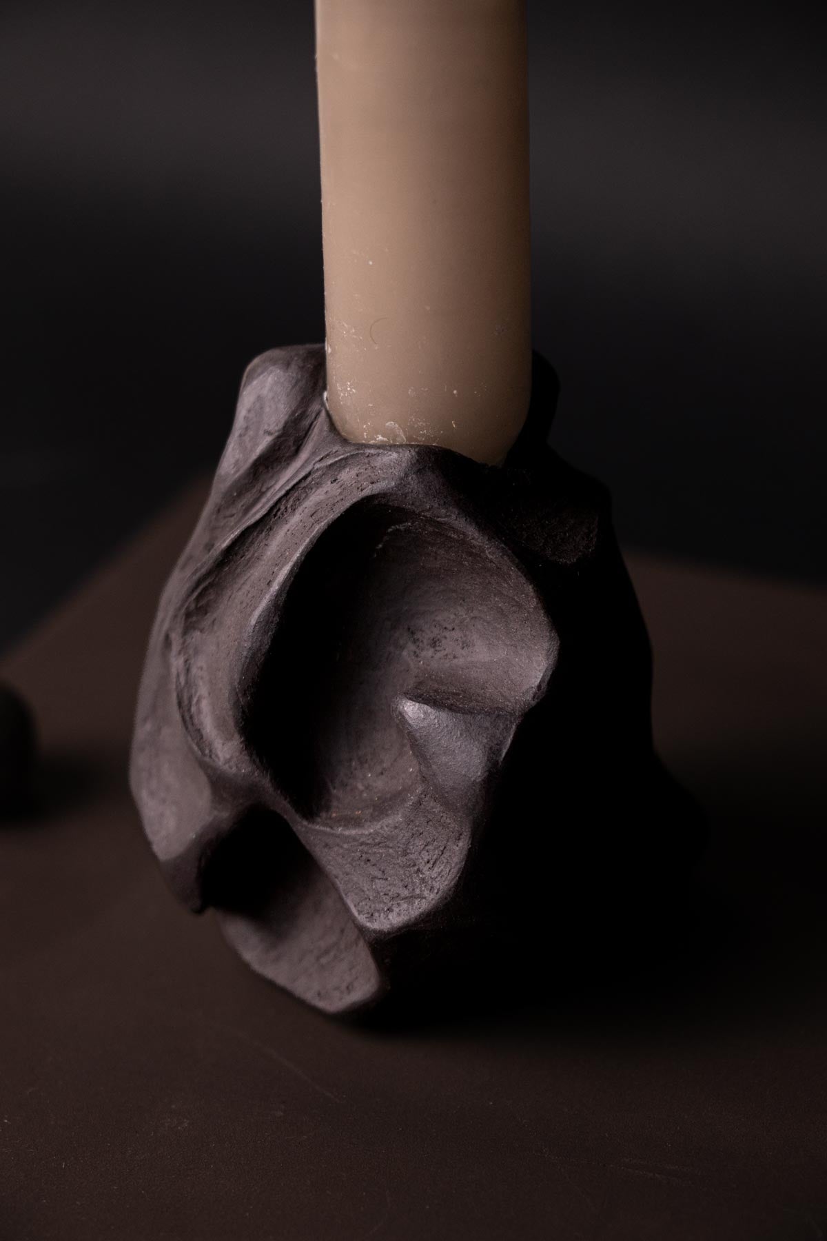 Decorative candle holder with a candle on a dark background. Contemporary ceramics. Ritual objects.