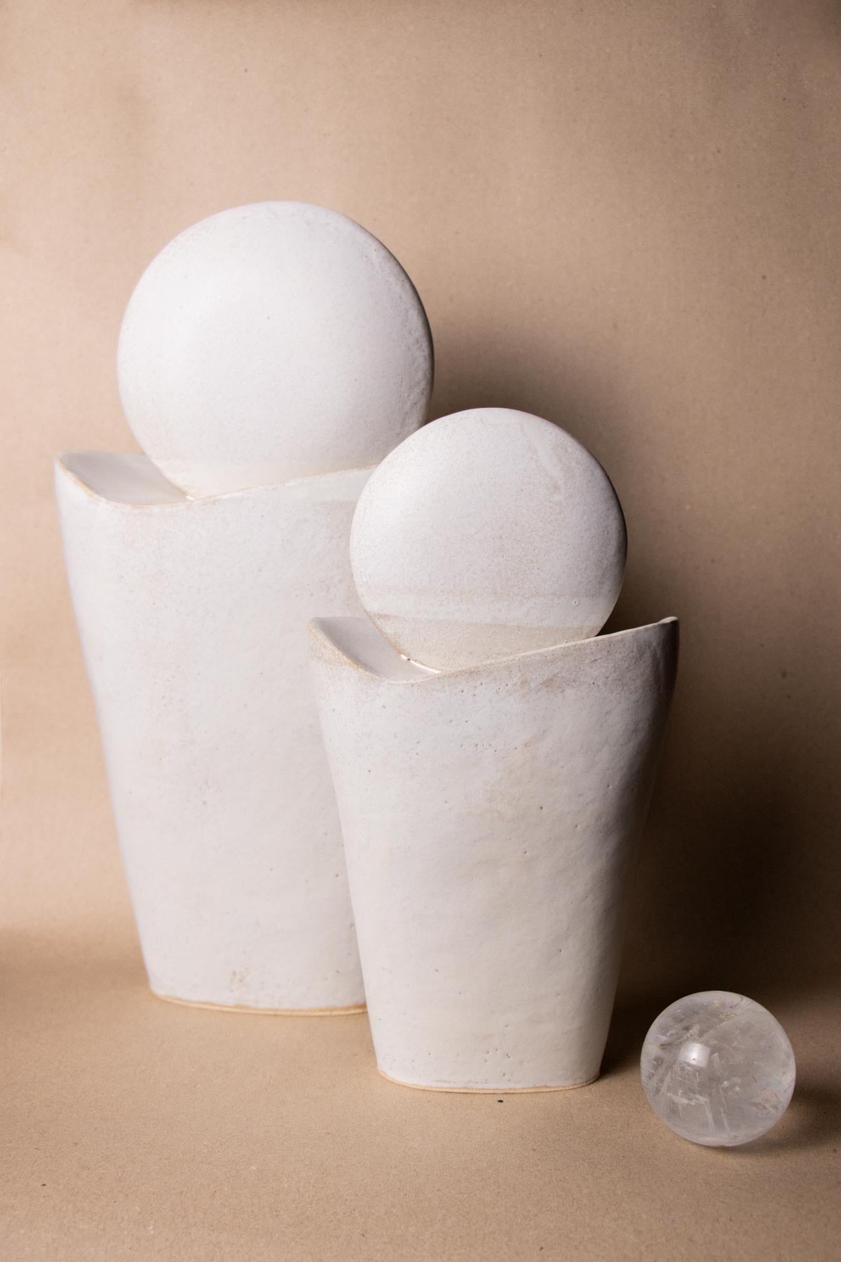 White ceramic sculptures on a beige background