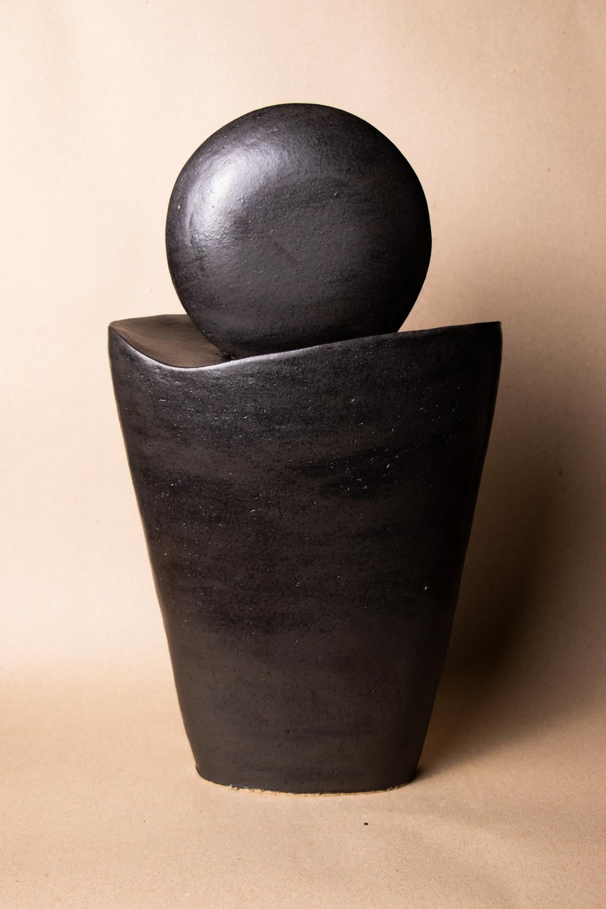 Black ceramic sculpture inspired by the moon. Minimalist stoneware sculpture. Minimalist decor.  Decorative ceramics. In front of a plain white background. New moon sculpture. Italian ceramics.